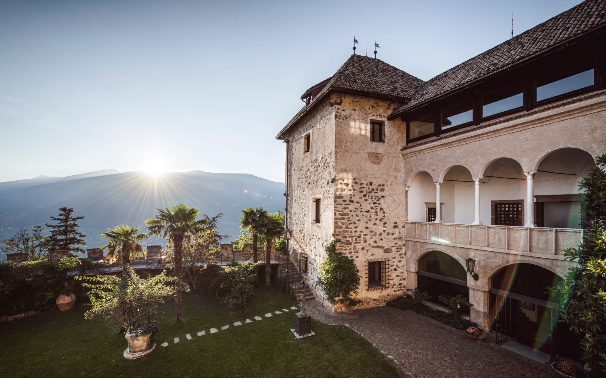 Historic Castel Fragsburg in Italy, showcasing its courtyard garden and stunning mountain views. Perfect Italian wedding venue.