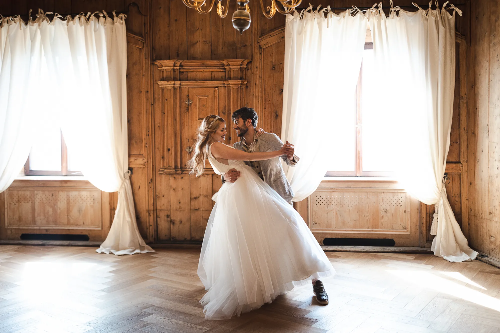 Happy couple dances at an Italian wedding in a wood-paneled room.