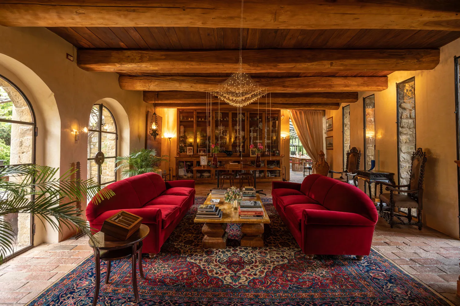 Luxurious living room at Castello Di Vicarello, a stunning castle wedding venue. Red velvet sofas and ornate details.