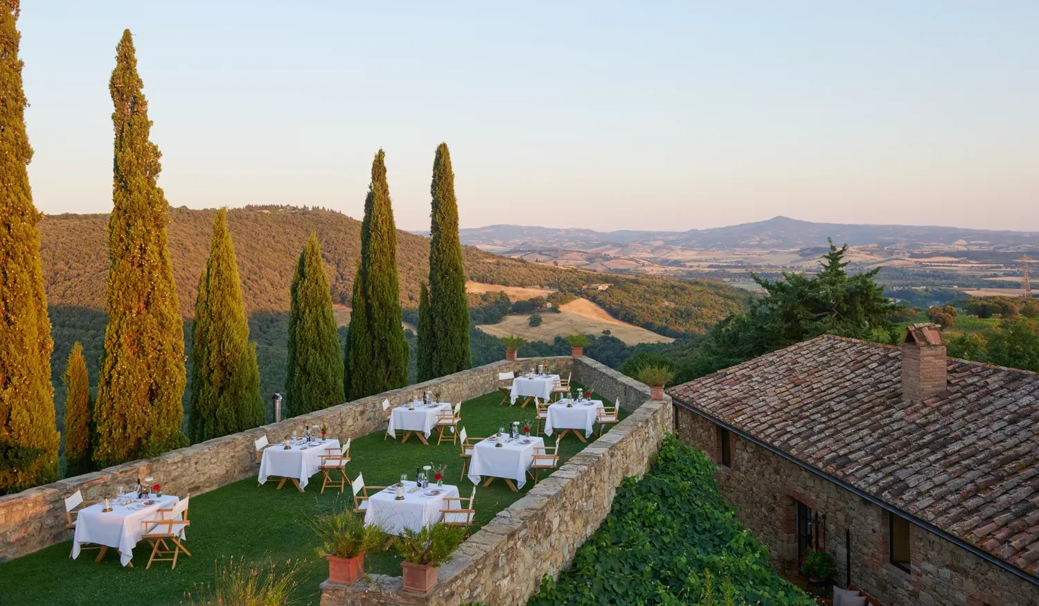 Romantic outdoor wedding reception at Castello Di Vicarello, featuring tables set on a lawn overlooking Tuscan hills.