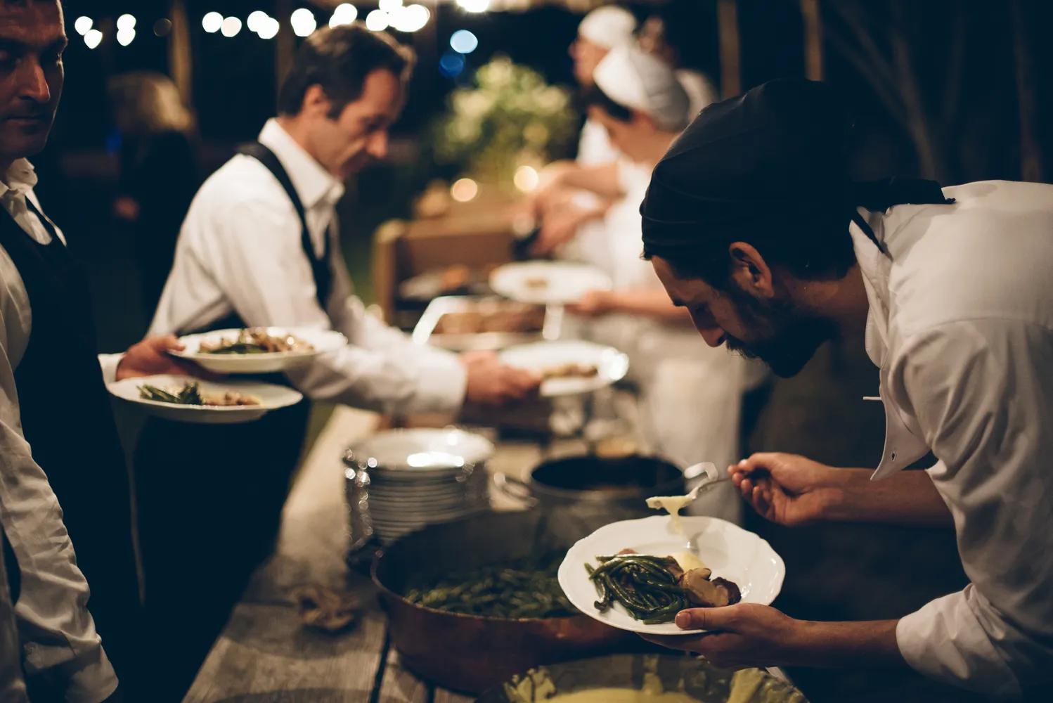 Catering staff preparing plates of food at a Castello Di Vicarello wedding.