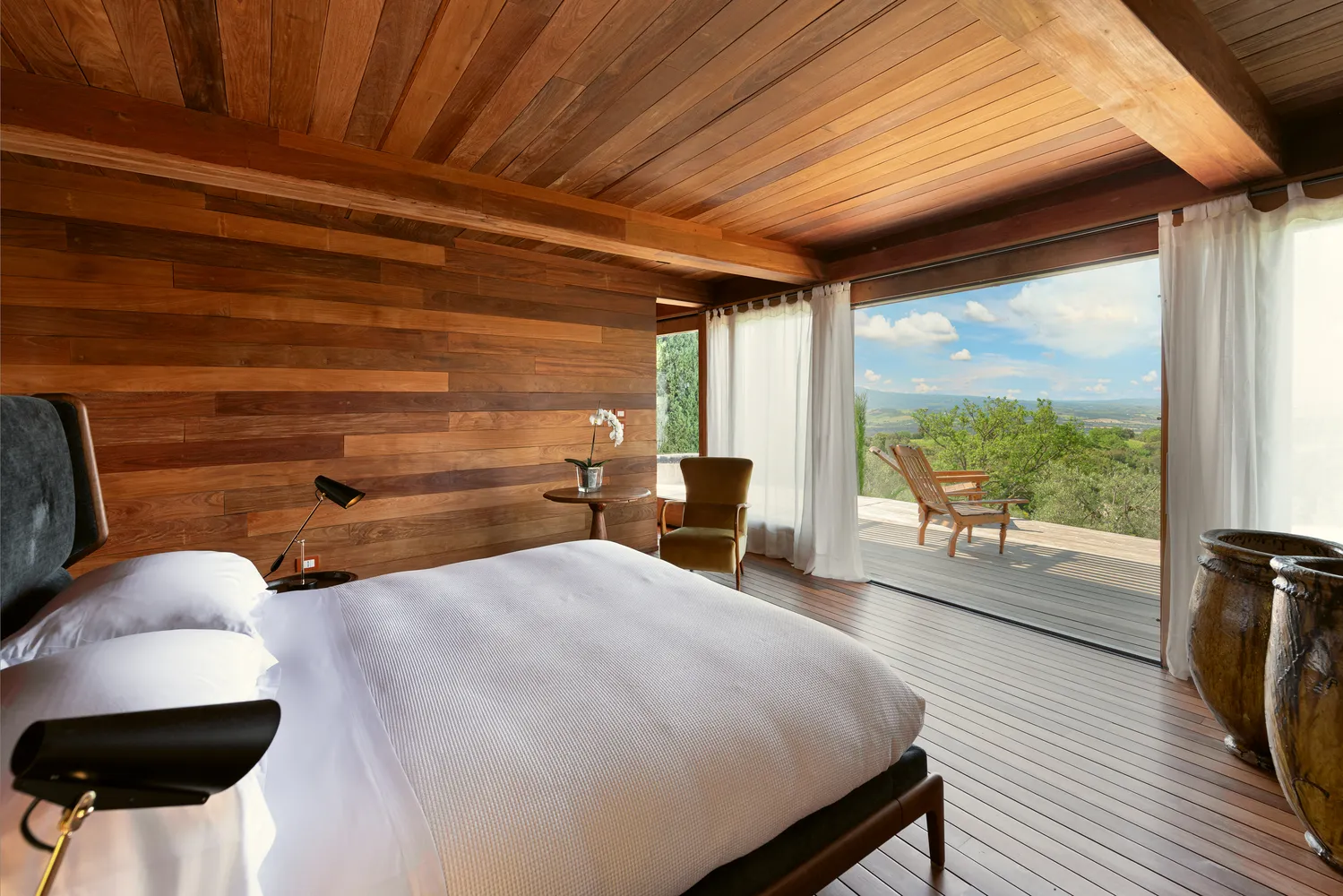 Luxurious bedroom with wooden walls and a stunning view, perfect for a Castello Di Vicarello wedding.