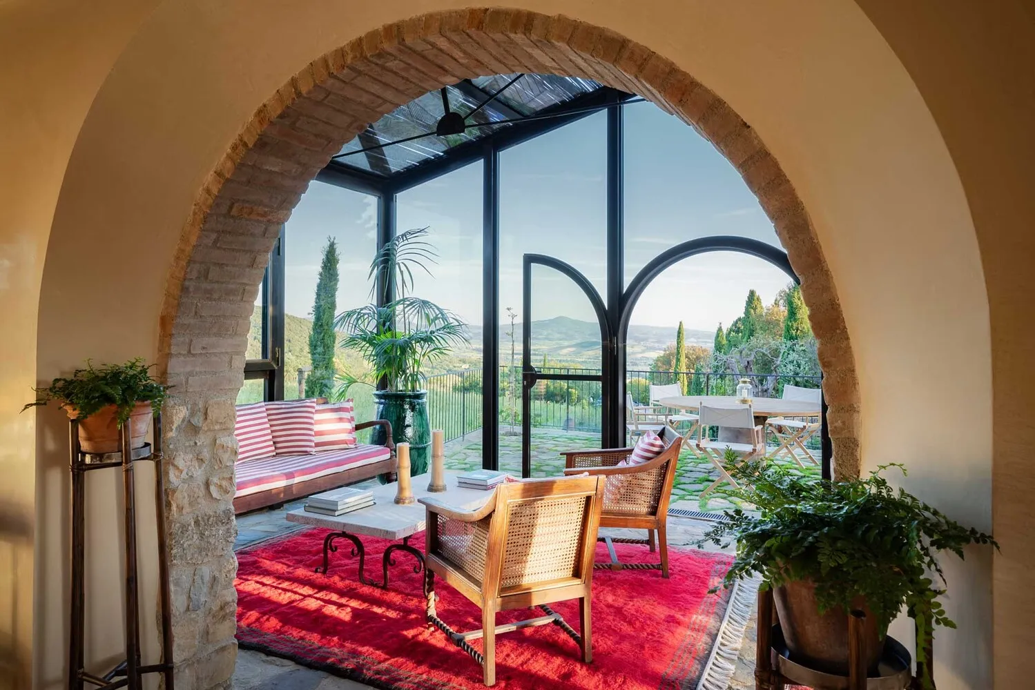 Sunlit Tuscan villa interior with arched doorway, showcasing a relaxing seating area and stunning vineyard views. Ideal for a Castello Di Vicarello wedding.