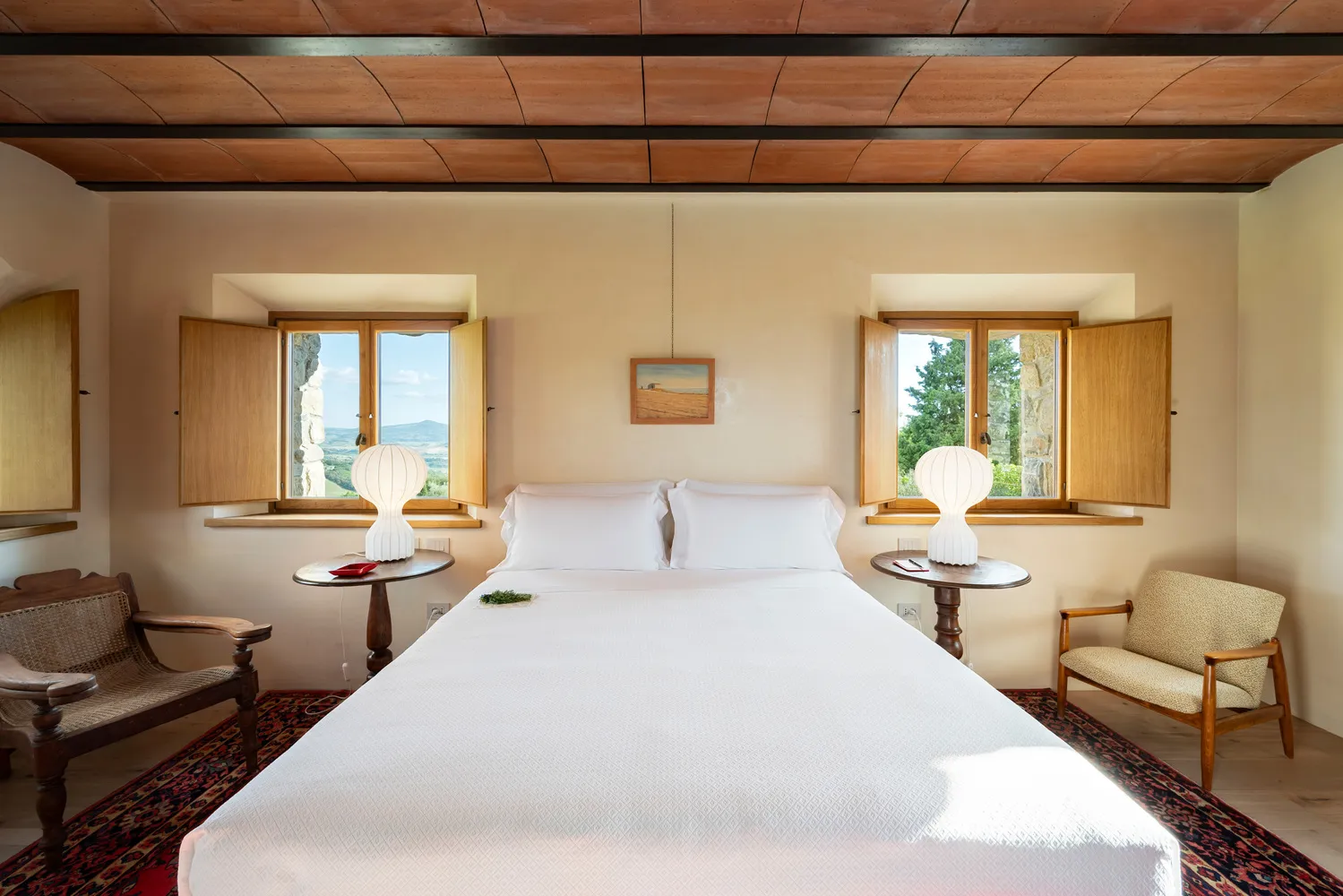 Bright bedroom at Castello Di Vicarello, featuring a large bed and views from two windows. Ideal castle wedding venue.