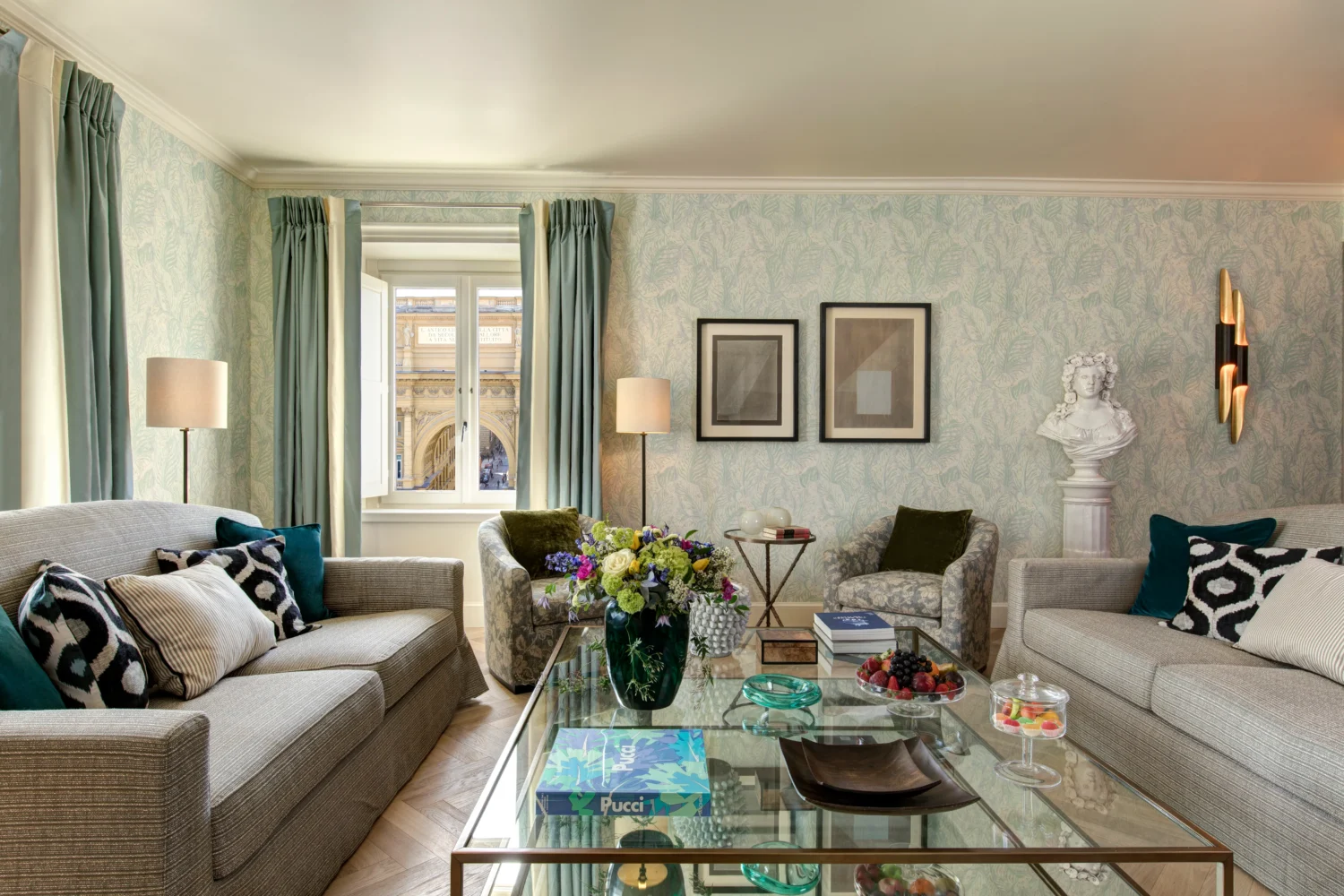Luxurious living room at Hotel Savoy, Florence, Italy. Features include elegant sofas, a glass coffee table, and a view of the city.
