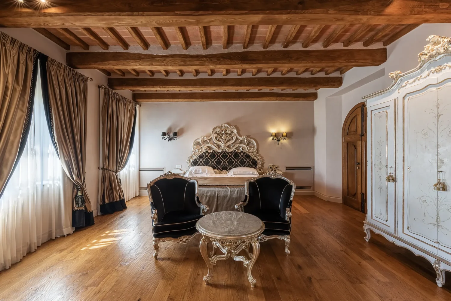 Elegant bedroom in Relais La Corte Dei Papi, featuring a large ornate bed and antique furniture. Perfect for an Italian Countryside Wedding.