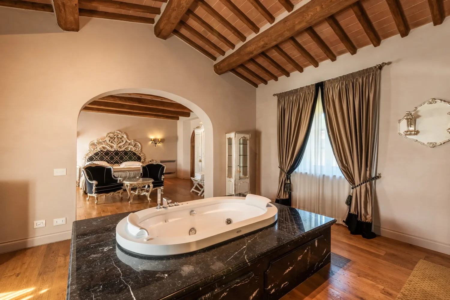 Luxury bathroom with jacuzzi tub, overlooking a bedroom in an Italian countryside villa. Perfect for a Relais La Corte Dei Papi wedding.