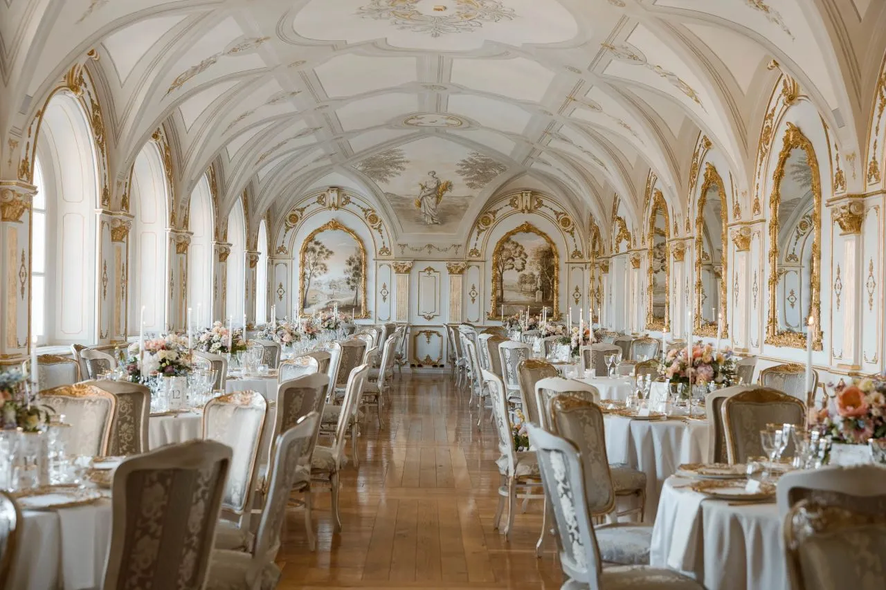 Elegant wedding reception in a grand Italian hall, featuring long tables adorned with floral centerpieces. Italian Countryside Wedding.