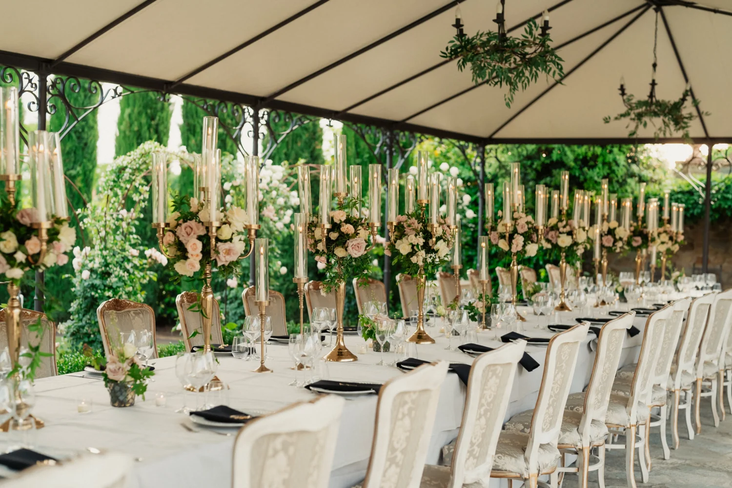 Elegant Italian countryside wedding reception table setting with candlelight and floral centerpieces.