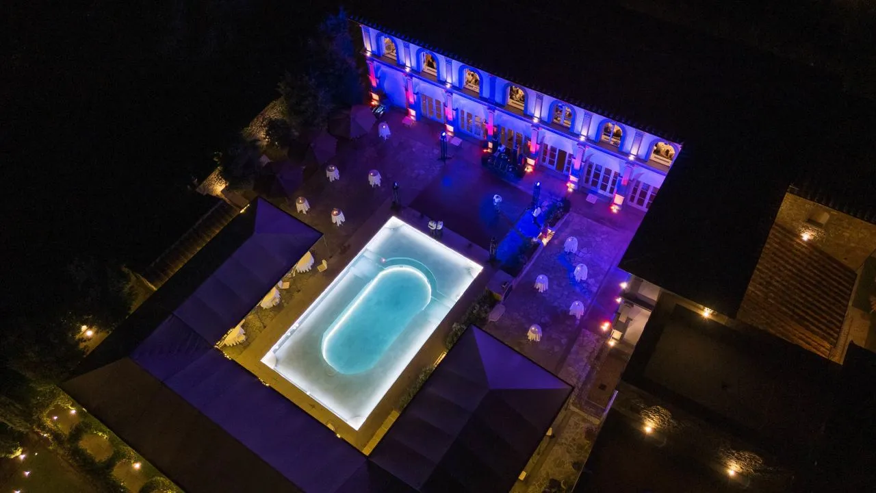 Aerial view of Relais La Corte Dei Papi at night, showcasing a pool and outdoor event space. Perfect Italian countryside wedding venue.