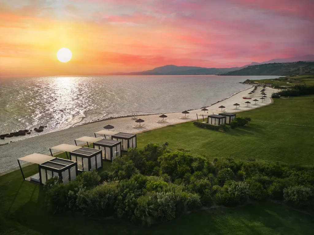 Stunning sunset view of Verdura Resort's beach in Sicily, featuring private cabanas and beach umbrellas. Perfect for a destination wedding.