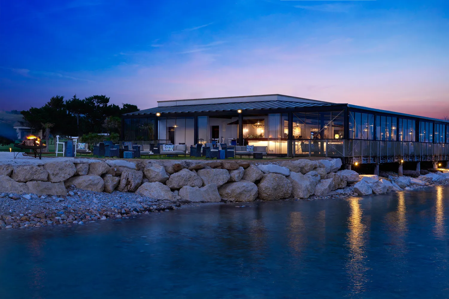 Verdura Resort in Sicily at dusk; outdoor seating overlooks the water. Ideal Sicily destination wedding venue.