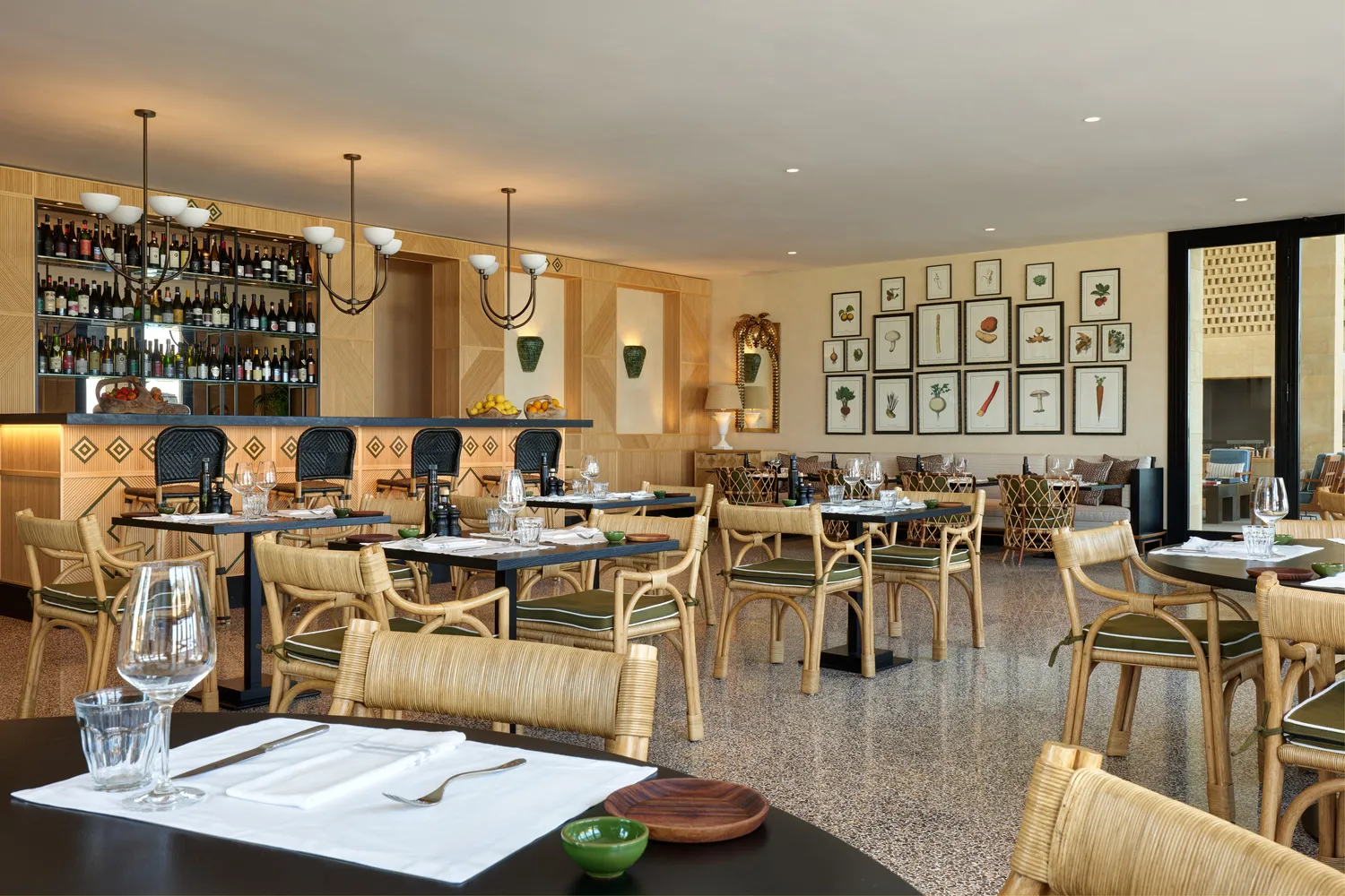 Elegant dining room at Verdura Resort, Sicily. Rattan chairs and a botanical art wall create a sophisticated atmosphere, perfect for a destination wedding.
