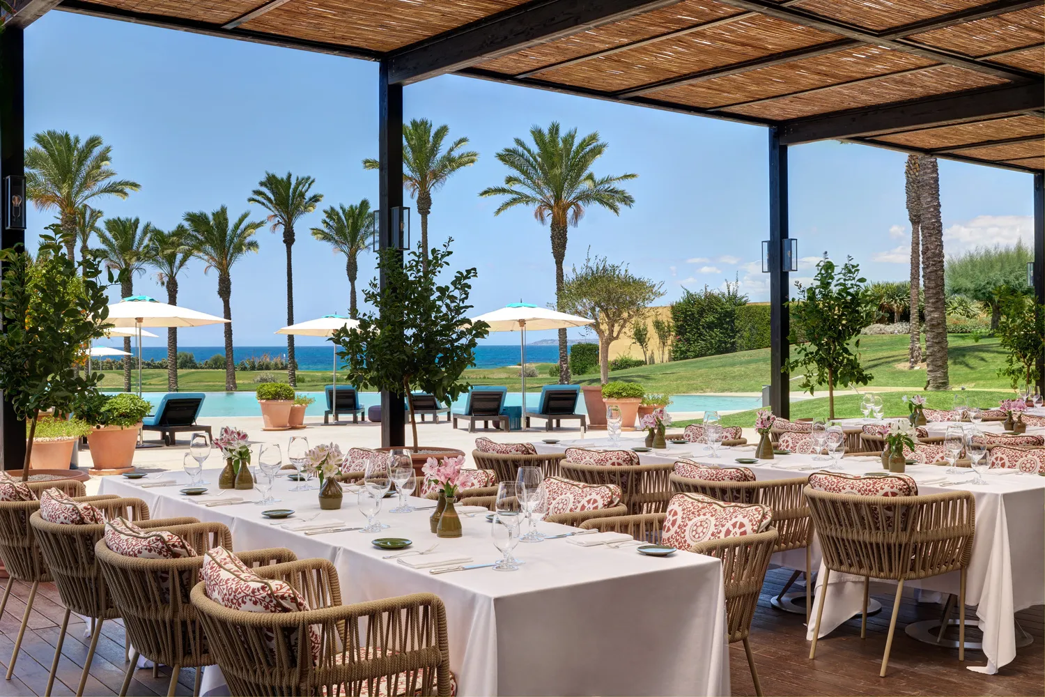 Outdoor dining area at Verdura Resort in Sicily, overlooking a pool and ocean. Ideal for a destination wedding.