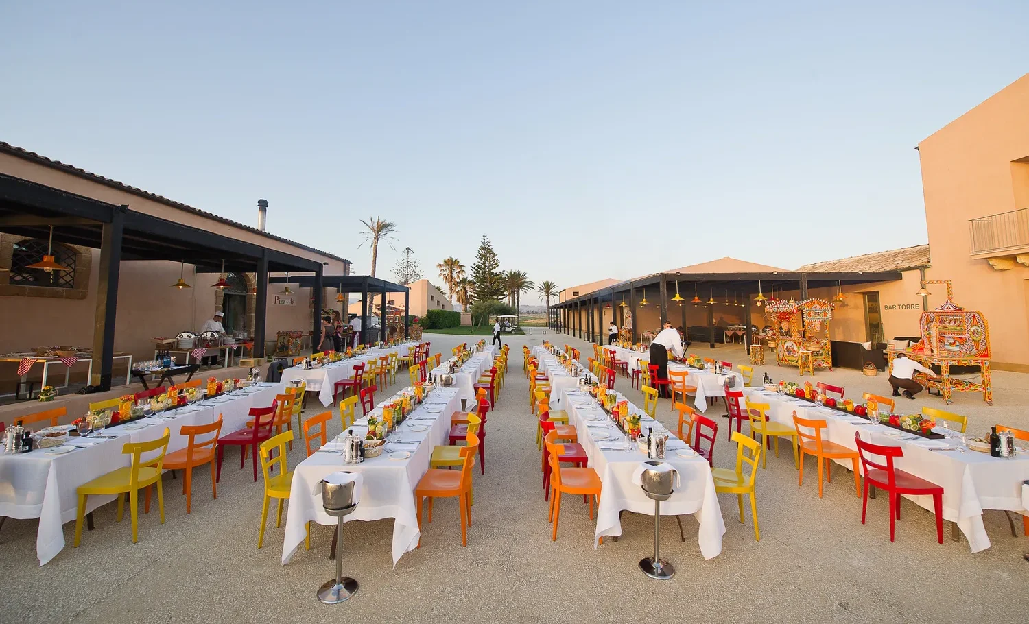 Elegant outdoor wedding reception at Verdura Resort in Sicily, featuring long tables with colorful chairs.