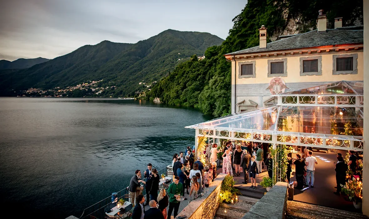 Guests mingle at a lakeside wedding reception at the stunning Villa Pliniana, a private Italian wedding villa.