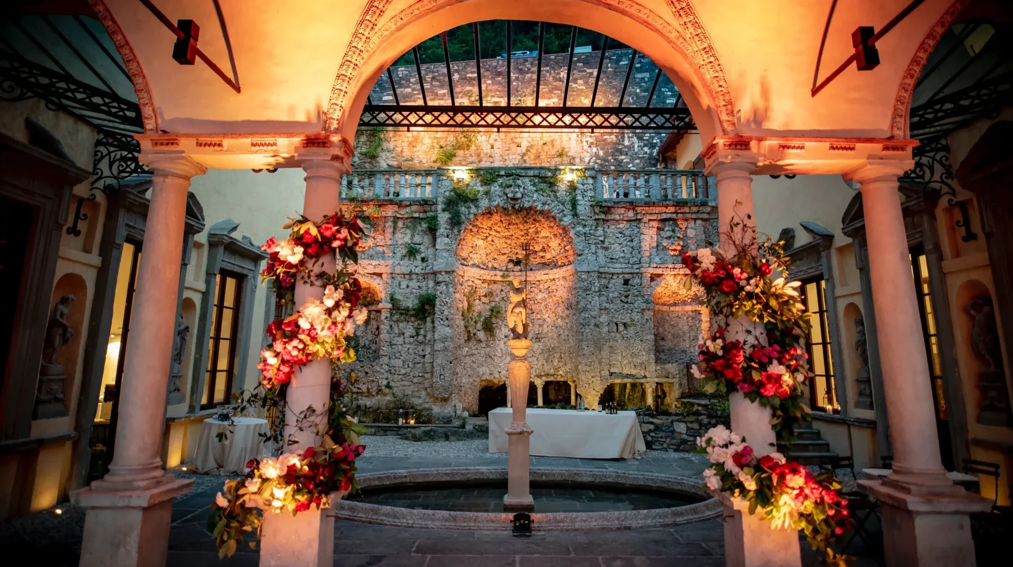 Romantic wedding reception at Villa Pliniana, a private Italian wedding villa. Floral decorations adorn the courtyard.