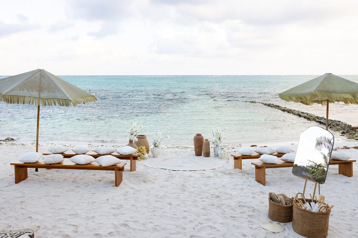 Beach wedding setup at Jashita Hotel Tulum, with benches, umbrellas, and ocean view. Tulum Wedding Venue.