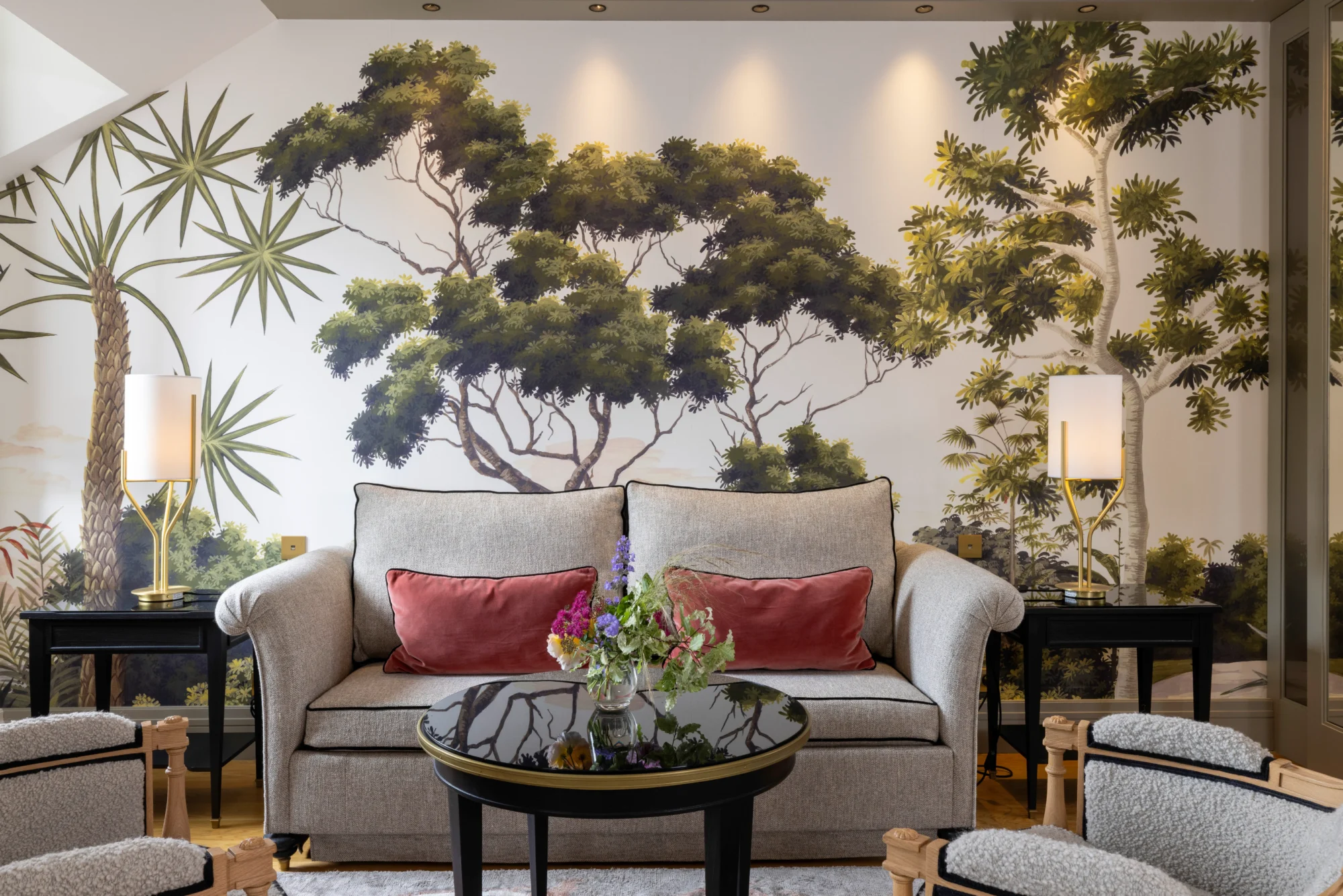 Elegant living room with gray sofa, floral arrangement, and a stunning botanical wall mural. Perfect for a luxurious French castle wedding.