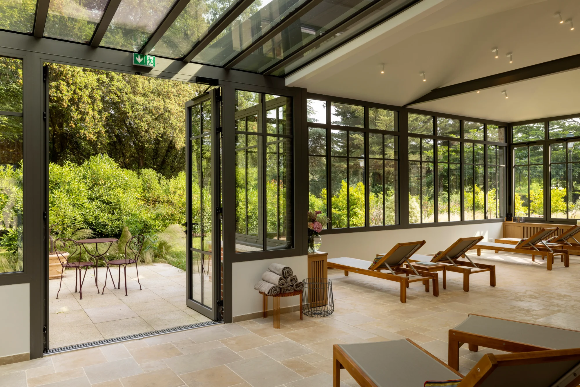 Sunlit relaxation room with wooden lounge chairs, overlooking a French garden. Perfect for a Domaine de la Bretesche wedding.