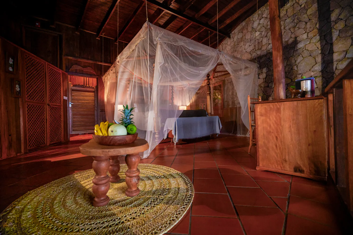 Romantic honeymoon suite at Ladera Resort with four-poster bed and fruit bowl.