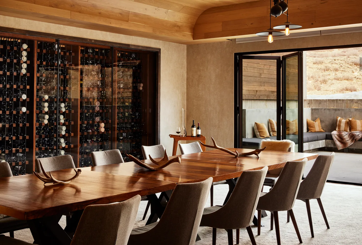 Elegant dining room at The Lodge at Blue Sky, Auberge Resorts Collection, featuring a long wooden table and a wine cellar.