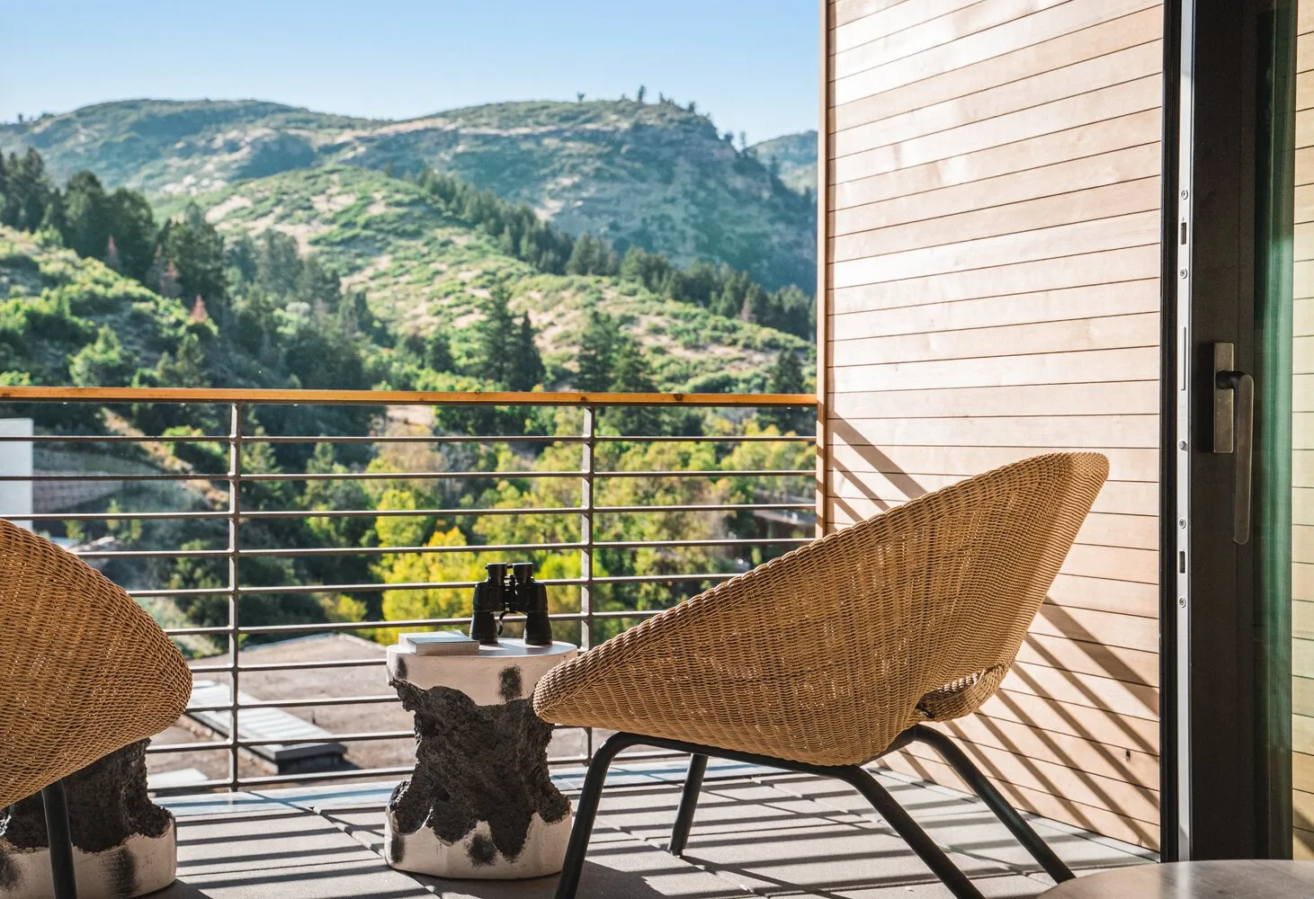 Two wicker chairs and a side table on a balcony overlooking a mountain view. Perfect for a Utah ranch wedding at The Lodge at Blue Sky.
