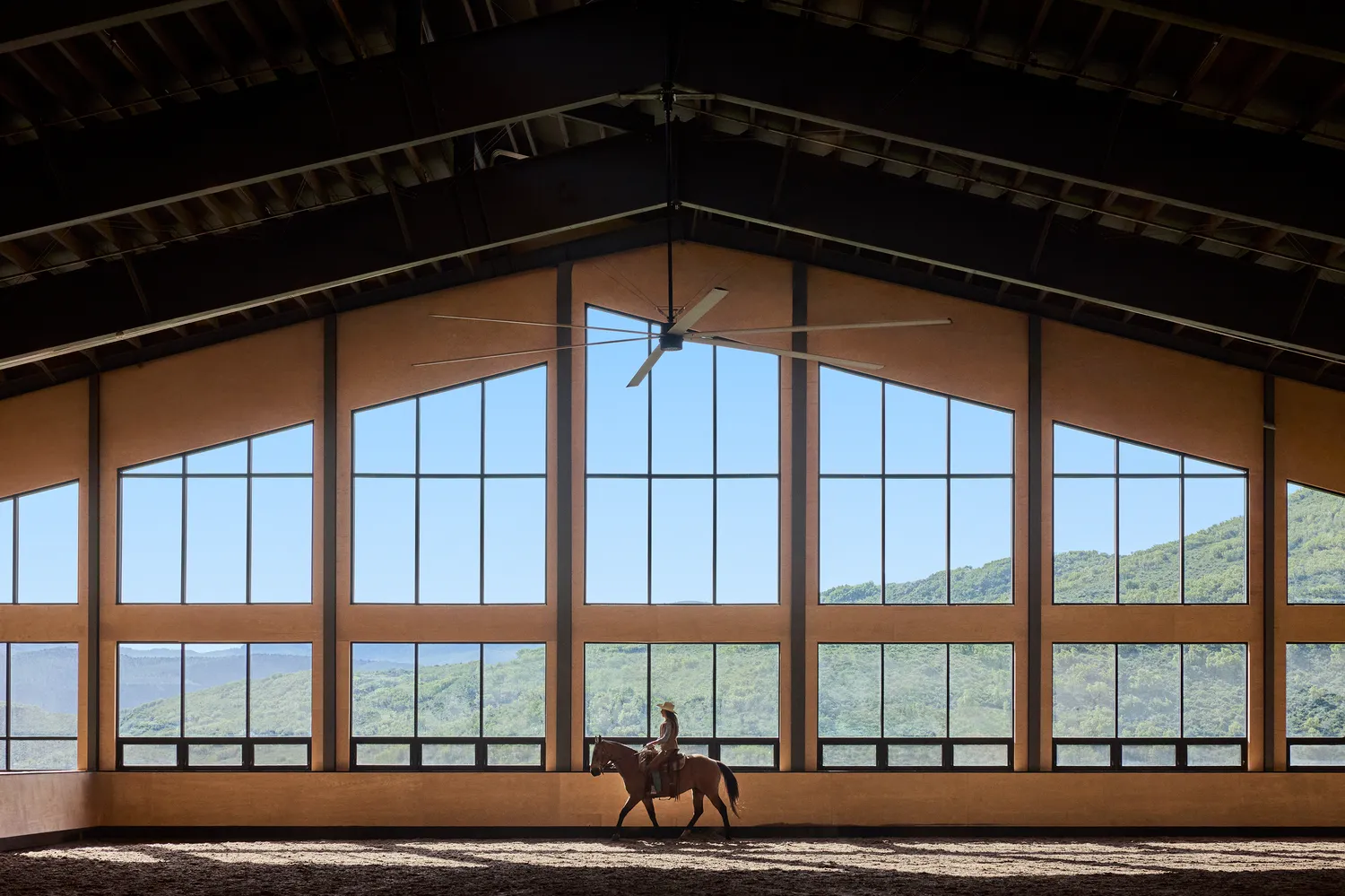 Horseback rider in a bright indoor arena overlooking Utah mountains. Perfect for a Utah ranch wedding at The Lodge at Blue Sky.