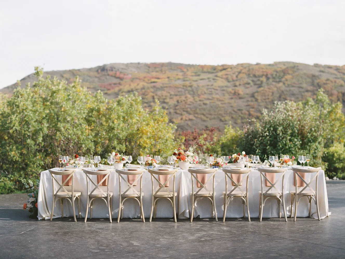 Elegant outdoor wedding reception table at The Lodge at Blue Sky, Auberge Resorts Collection in Utah. Long table with floral centerpieces and cross-back chairs.