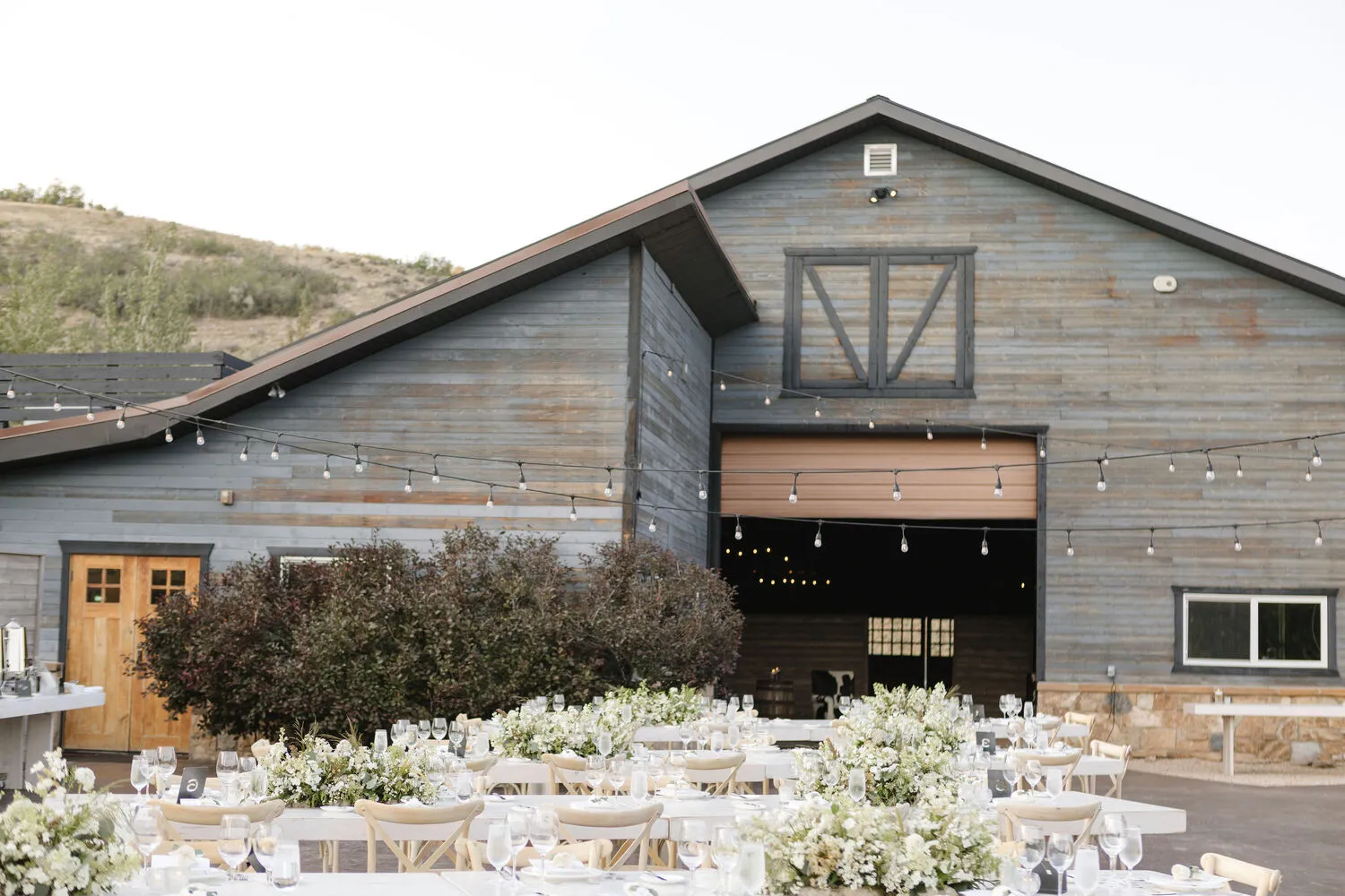 Elegant outdoor wedding reception at The Lodge at Blue Sky, Auberge Resorts Collection in Utah. Long tables adorned with white flowers.