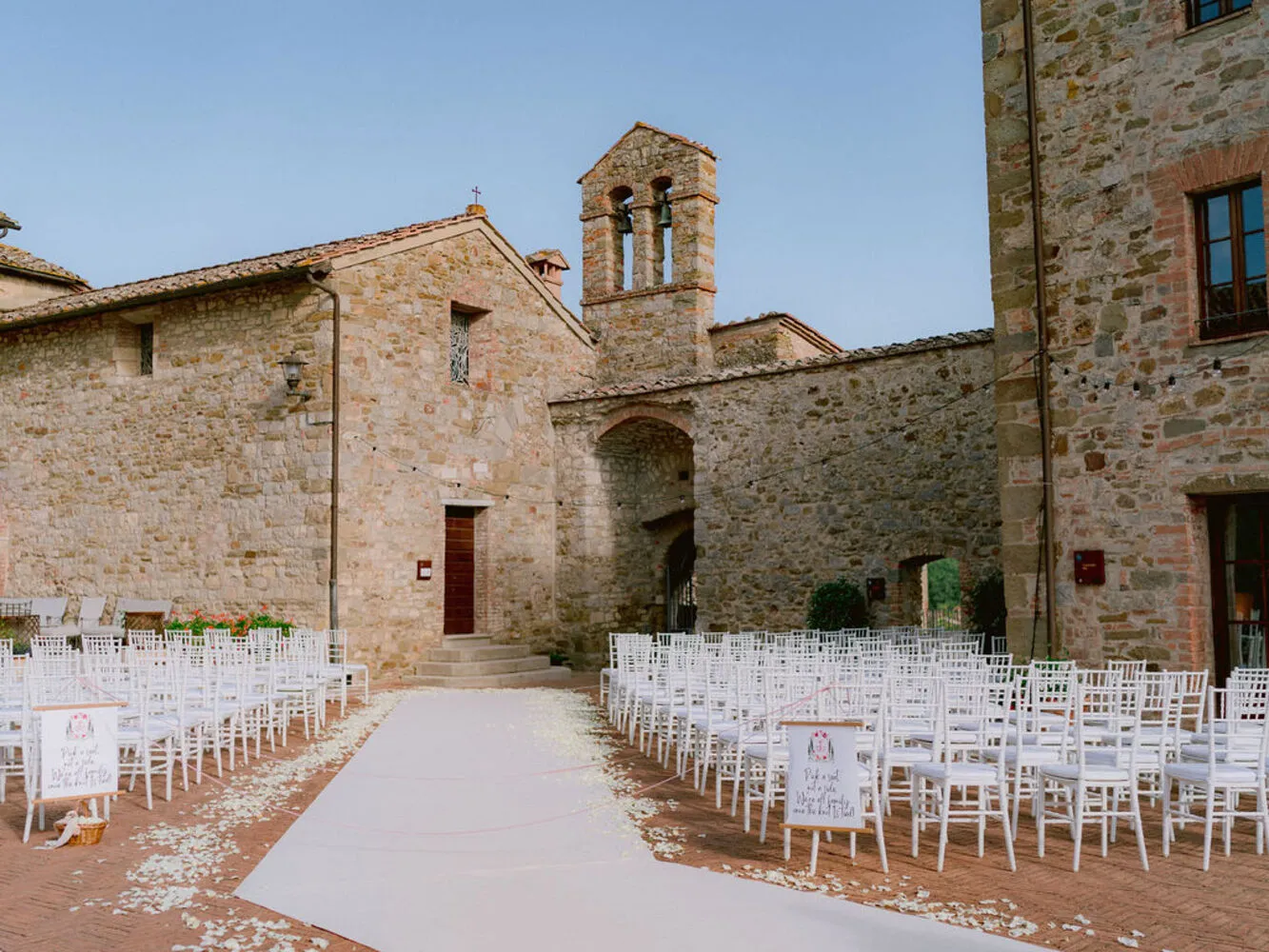 Outdoor wedding ceremony setup at Castel Monastero in Tuscany. White chairs and aisle runner.