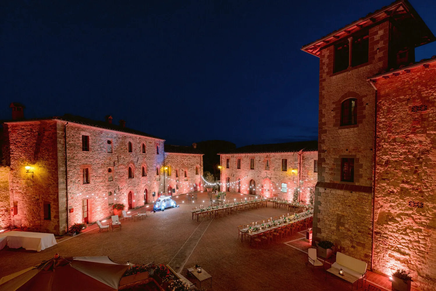 Romantic Tuscany wedding reception at Castel Monastero, featuring long tables and string lights.