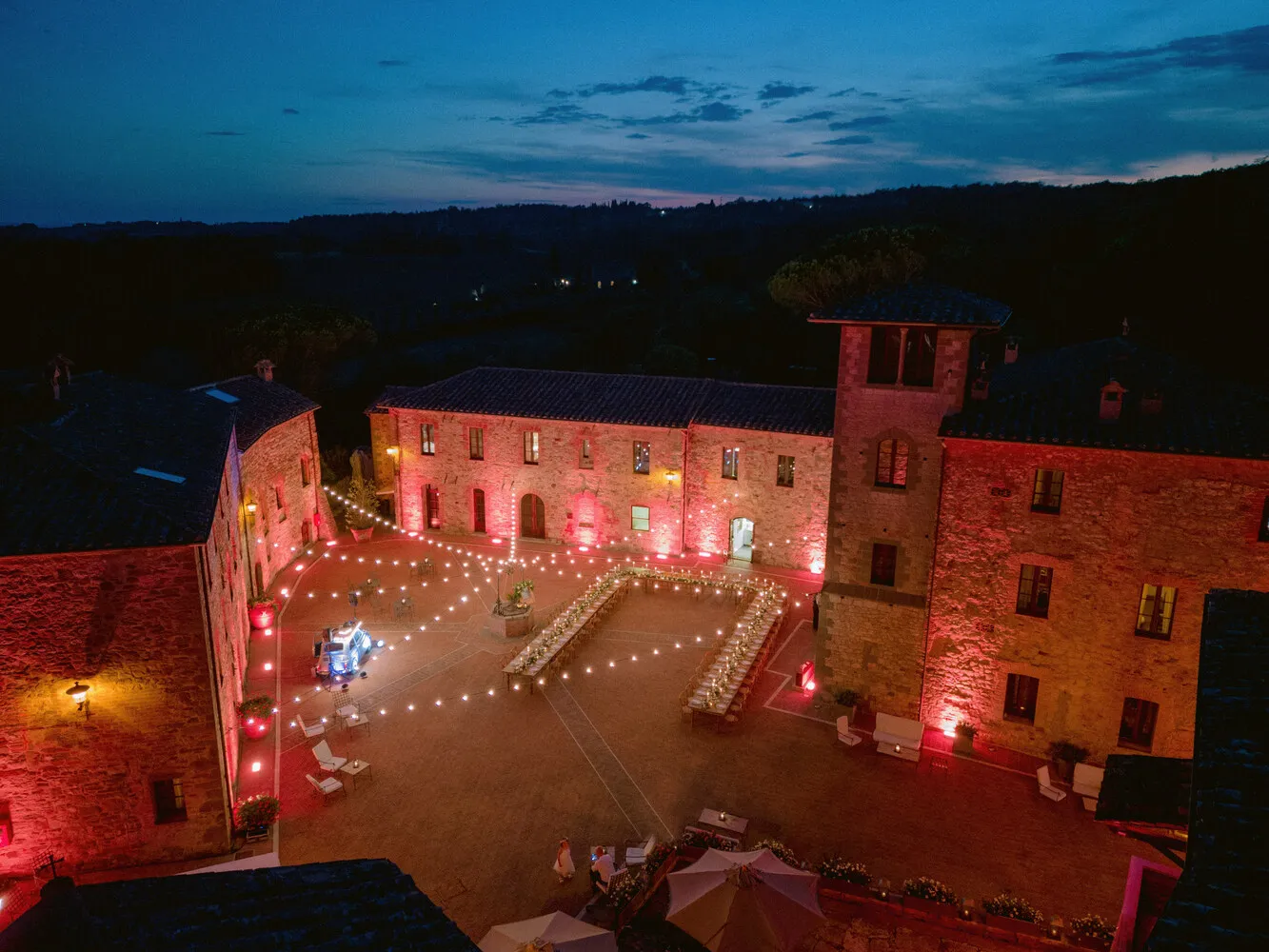 Romantic Tuscany wedding reception at Castel Monastero. String lights illuminate the courtyard.