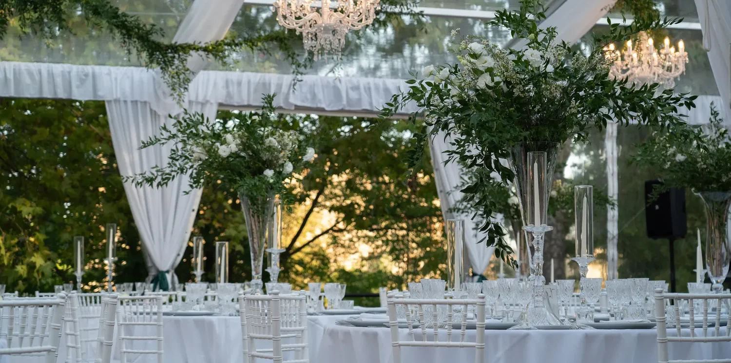 Elegant outdoor wedding reception tables at Castel Monastero in Tuscany, featuring white linens, crystal candelabras, and lush greenery.