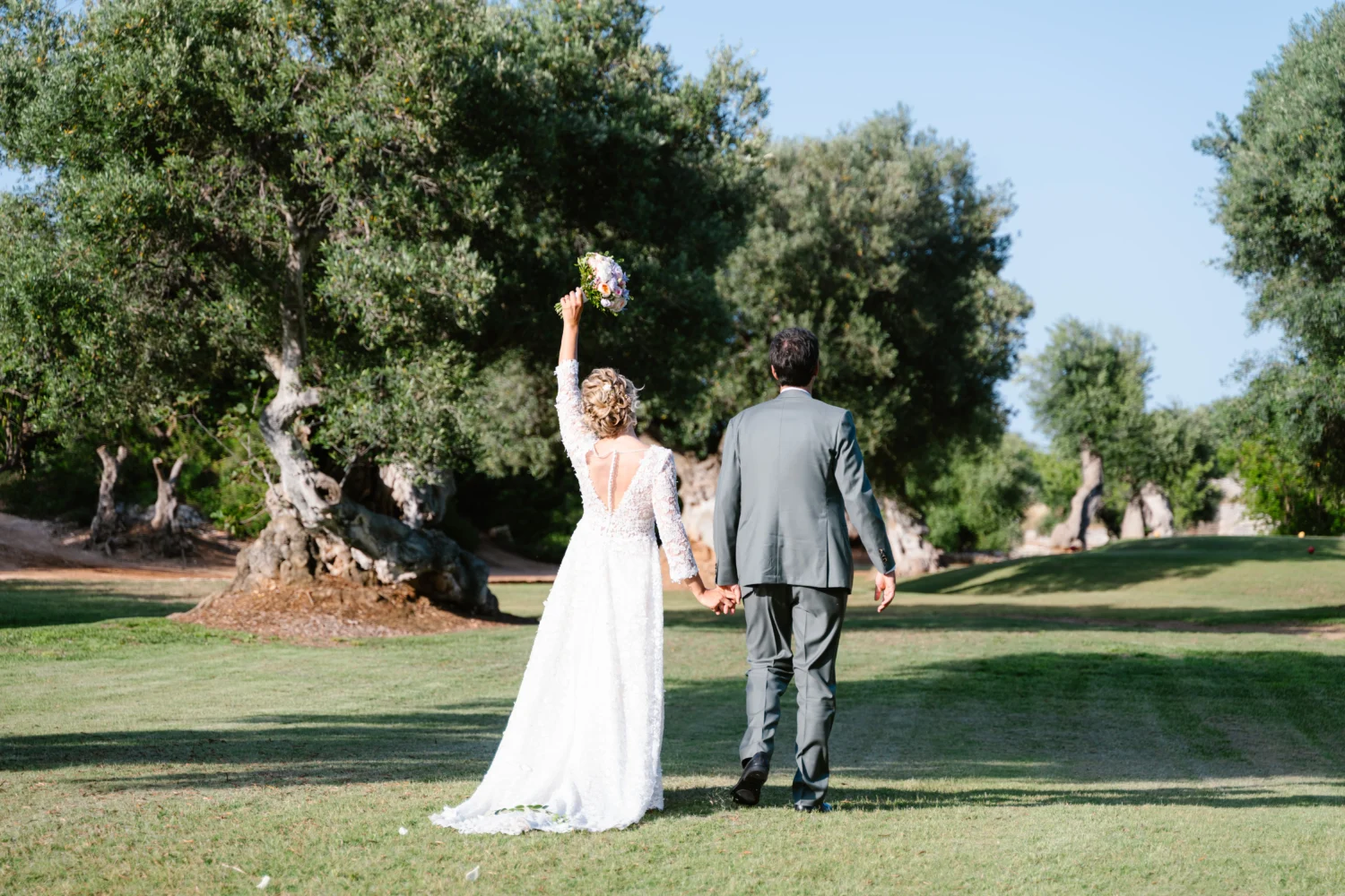 Bride and groom holding hands, walking away in Puglia. Puglia wedding at Masseria Torre Maizza.