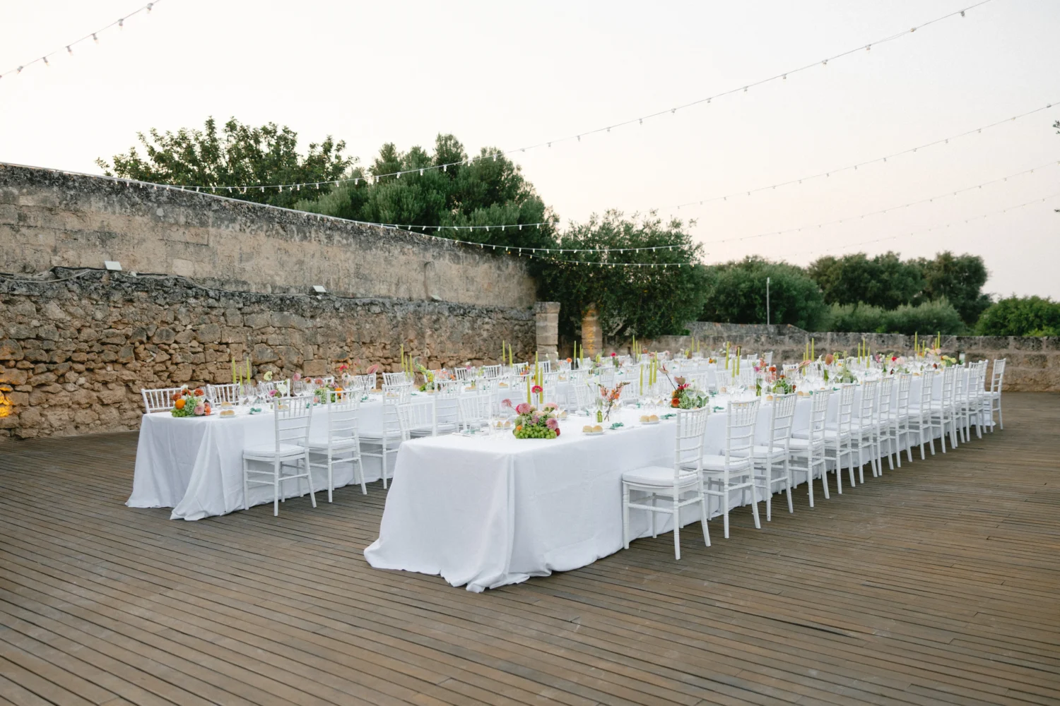 Elegant Puglia wedding reception at Masseria Torre Maizza, featuring long tables with white linens and floral centerpieces.