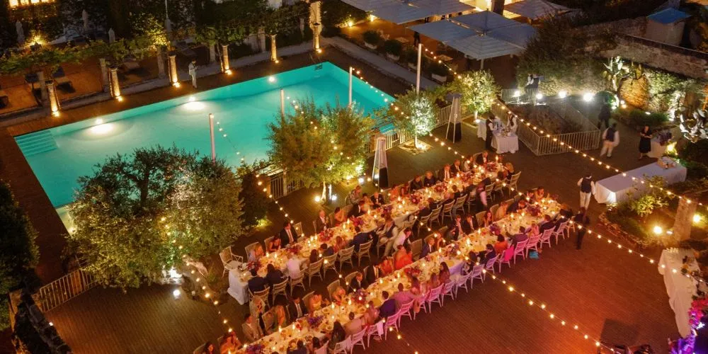 Romantic Puglia wedding reception at Masseria Torre Maizza, featuring long tables with candlelight and a pool in the background.