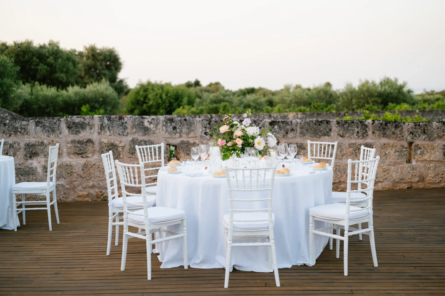 Elegant Puglia wedding reception table setting at Masseria Torre Maizza. White chairs and floral centerpiece.