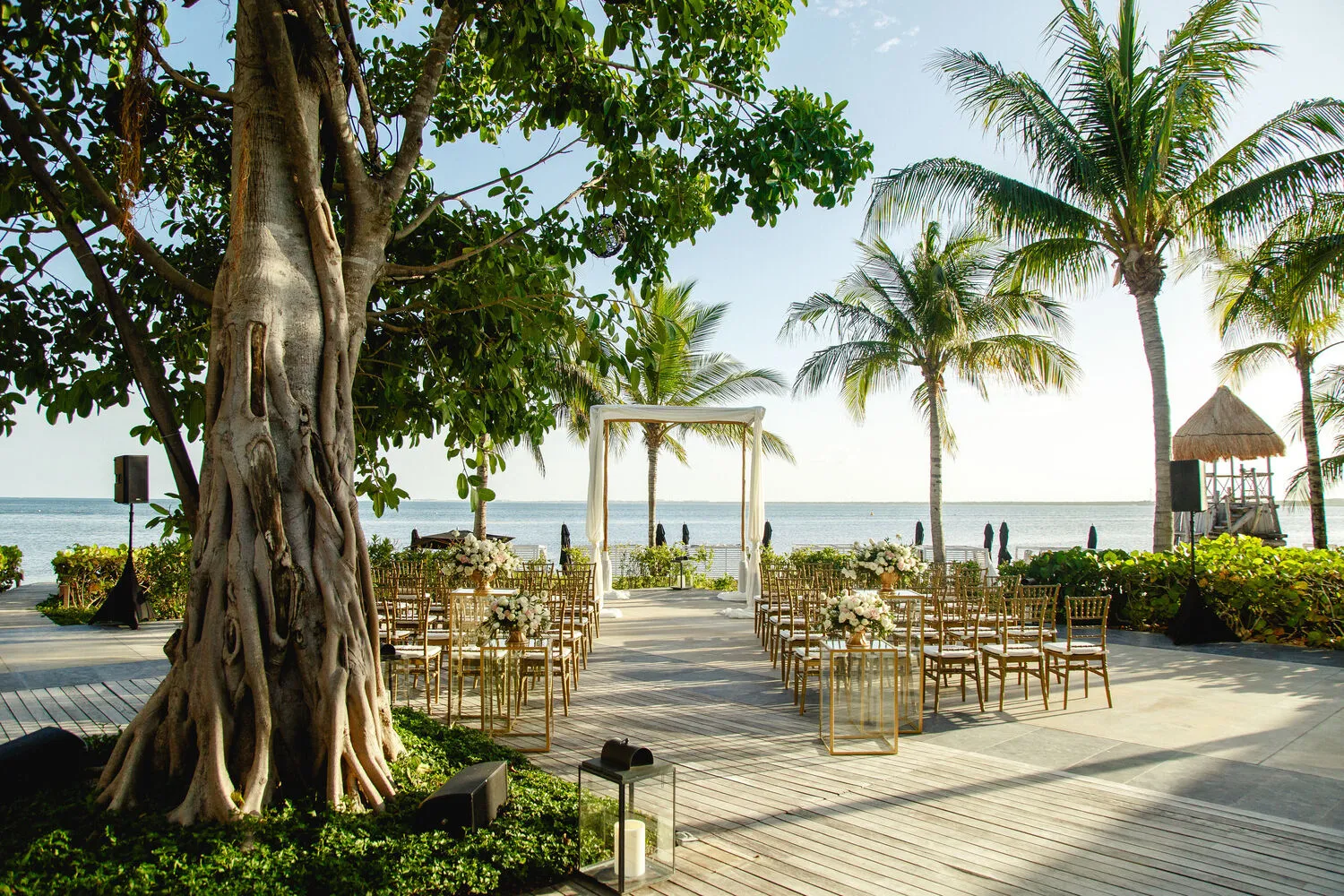 Beachfront wedding ceremony setup at NIZUC Resort & Spa in Cancun, featuring gold chairs and floral arrangements. Perfect for Cancun weddings and honeymoons.