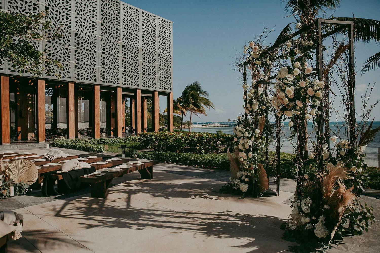 Elegant Cancun wedding ceremony setup at NIZUC Resort & Spa, featuring floral arch and ocean view.