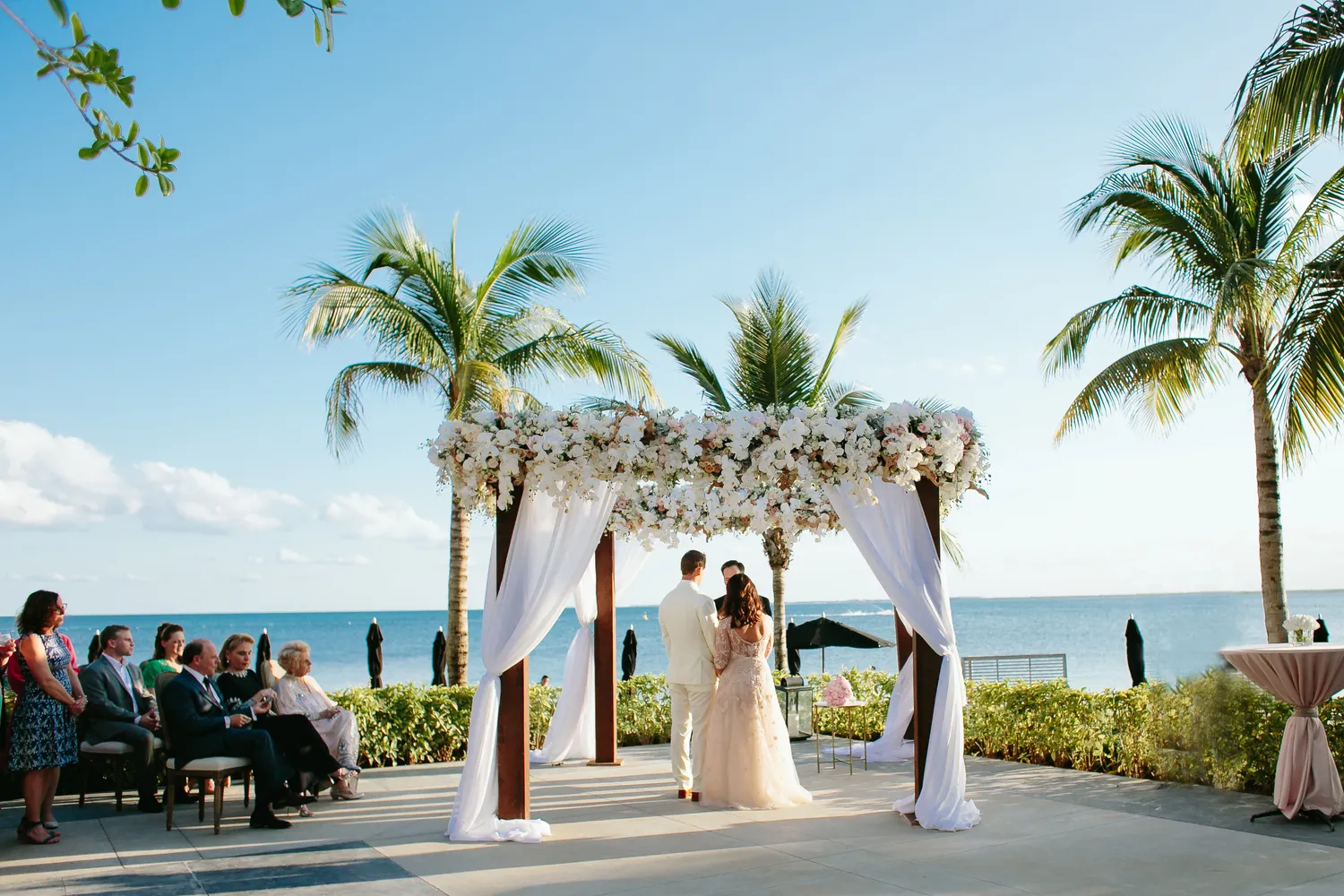 Cancun wedding ceremony at NIZUC Resort & Spa. Bride and groom exchange vows under a floral archway.
