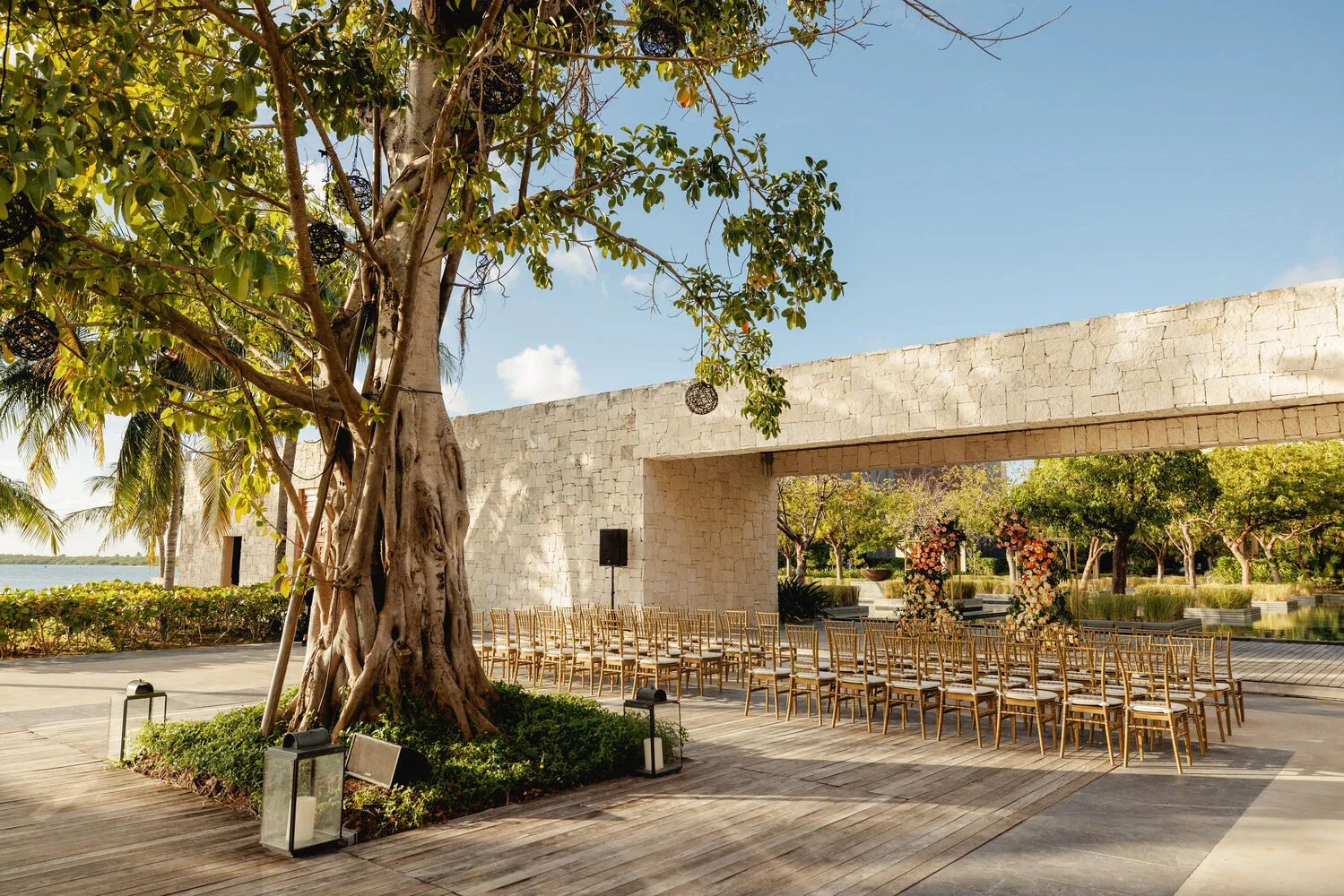 Outdoor Cancun wedding ceremony setup at NIZUC Resort & Spa, featuring gold chairs and floral arch.