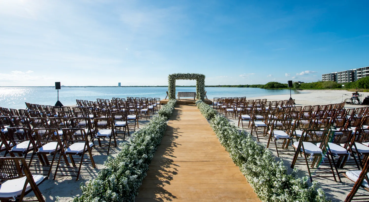 Beach wedding ceremony setup at NIZUC Resort & Spa in Cancun. Rows of chairs face a floral archway.