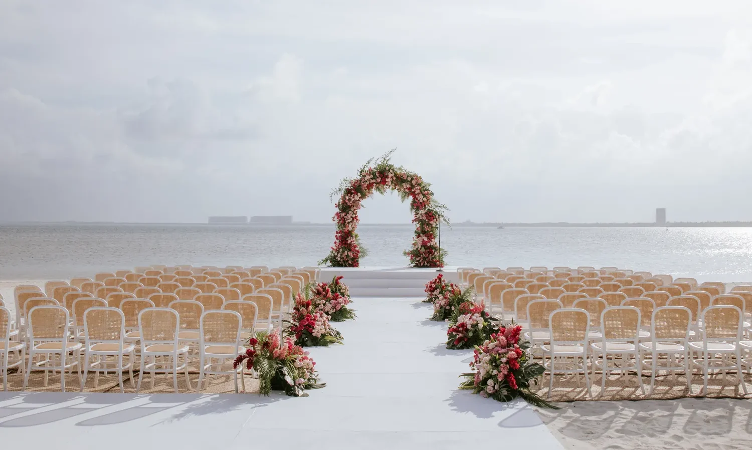 Beach wedding ceremony setup at NIZUC Resort & Spa in Cancun. Floral arch and aisle decor.