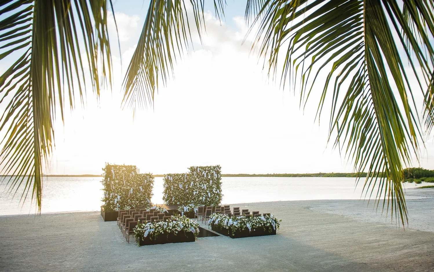 Beach wedding ceremony setup at NIZUC Resort & Spa in Cancun, featuring floral arrangements and chairs.