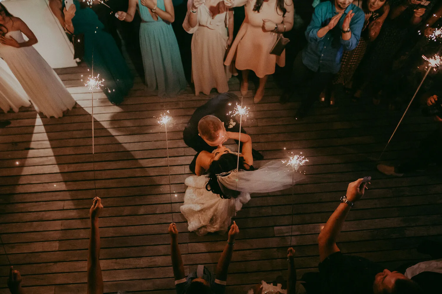 Newlyweds kiss under sparklers at a Cancun wedding reception.