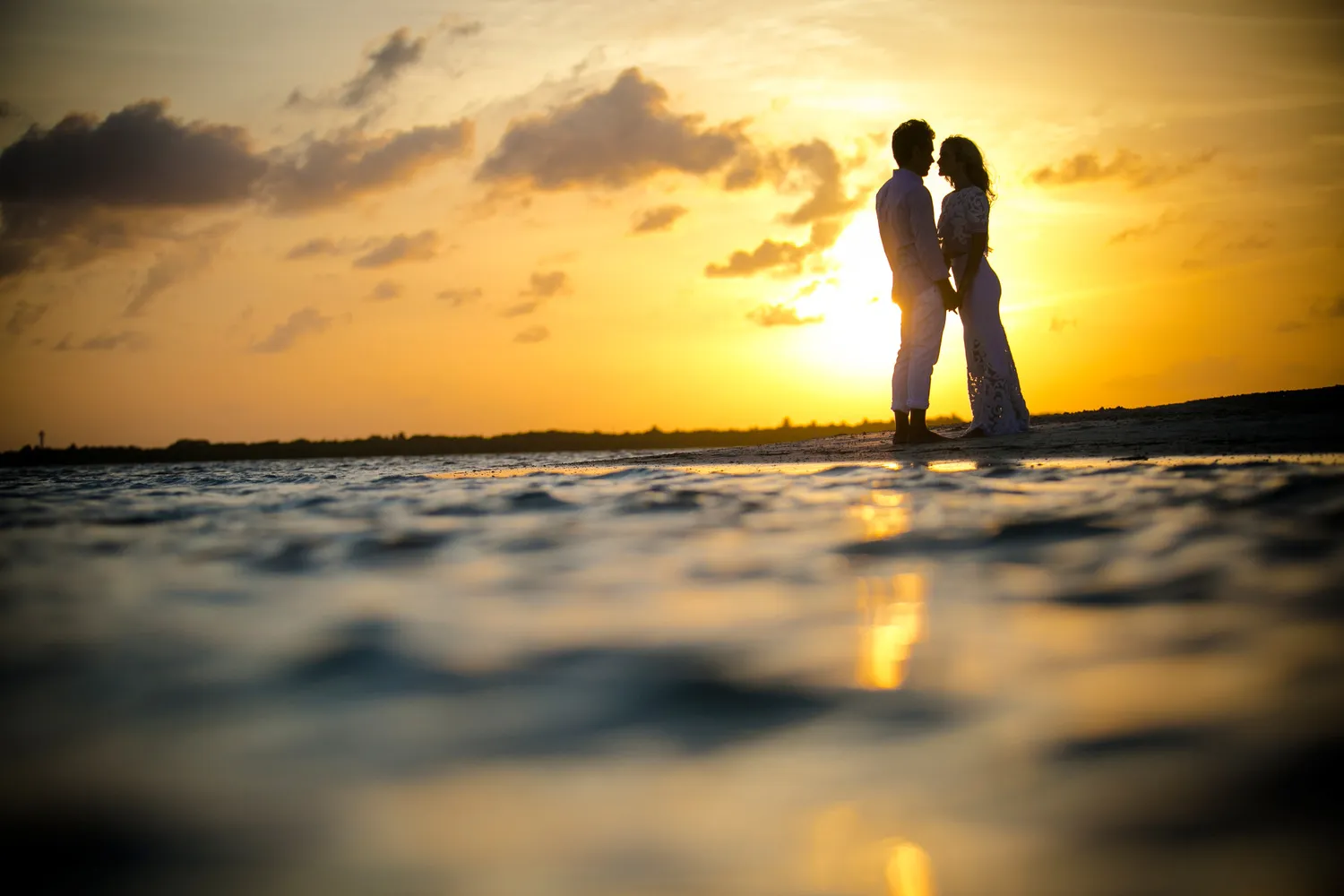 Silhouette of couple embracing at sunset on Cancun beach. Perfect for a NIZUC Resort & Spa honeymoon or wedding.