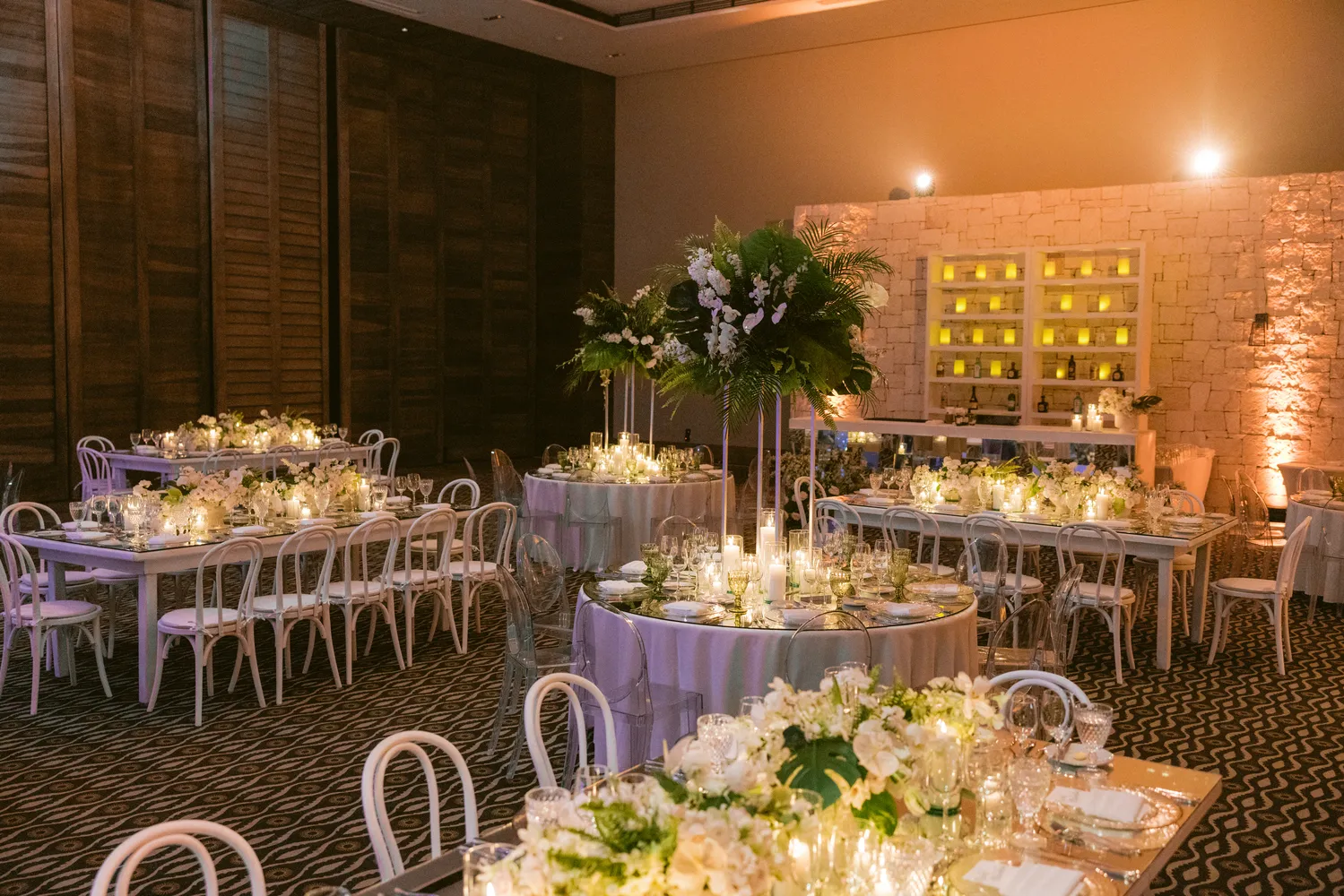 Elegant Cancun wedding reception at NIZUC Resort & Spa, featuring white tables, chairs, and lush floral centerpieces.