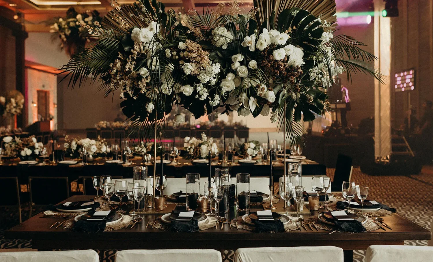 Elegant Cancun wedding reception at NIZUC Resort & Spa, featuring a stunning floral centerpiece and dark wood table settings.