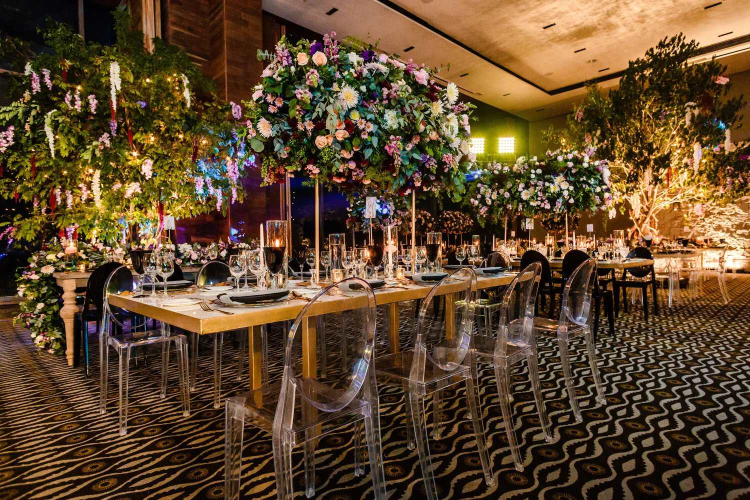 Elegant Cancun wedding reception at NIZUC Resort & Spa, featuring a long table with clear chairs and stunning floral arrangements.